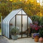 Arched greenhouse in a backyard with the text: Greenhouse Orientation: Secrets to Perfect Plant Growth