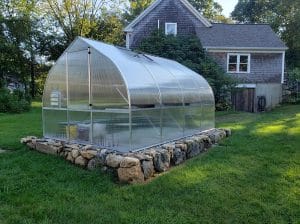 Riga 4 Greenhouse with rock foundation in the backyard of a house