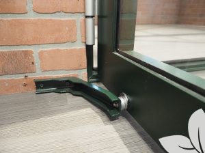 Door holder installed on a greenhouse on a stem wall, holding the hinged door open securely