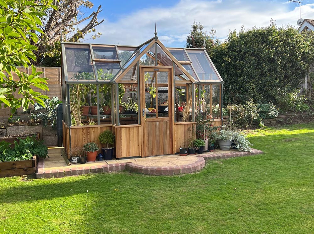 T-Shaped wooden greenhouse in a backyard on a sunny day