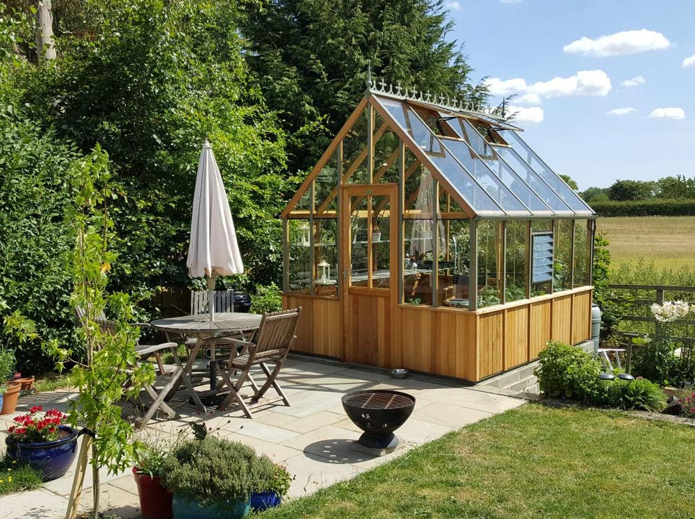 Conventional wooden glass greenhouse near patio setting