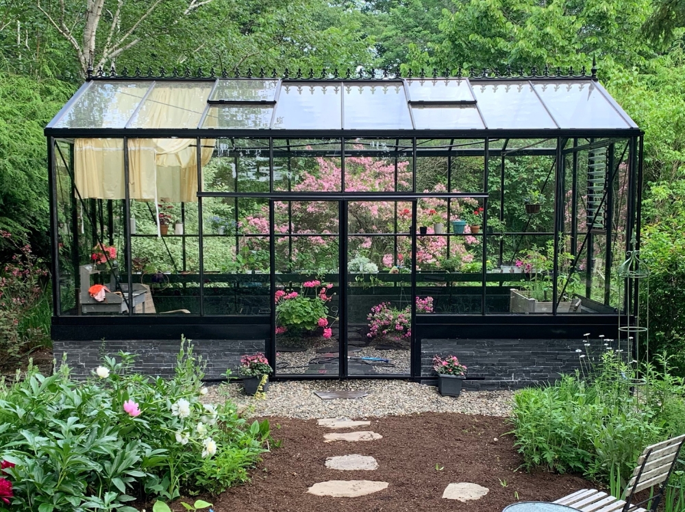 A peaceful glass greenhouse showing how to use a greenhouse for gardening.
