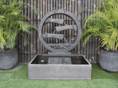 Large black 36" diameter wagon wheel fountain with three flumes coming out of the middle with water cascading down them and into a 39” W x 31” D x 10” H square base. Made of high-strength glass-reinforced concrete, uses a 925 GPH pump, and weighs 838 lbs.
