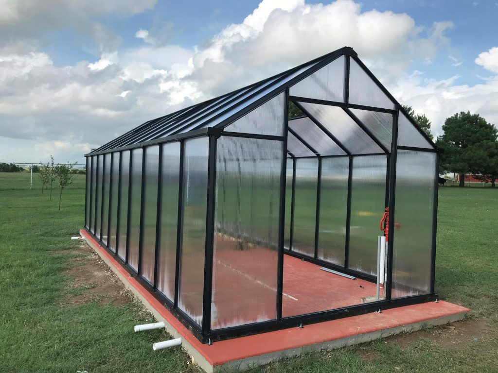 Mont greenhouse under construction with panels installed no door on concrete foundation