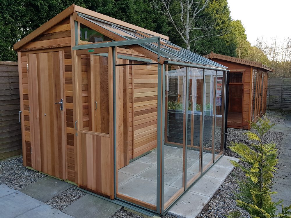 A small combination greenhouse that is gable shaped with half as a shed and the other half a lean-to greenhouse with a sliding door. 