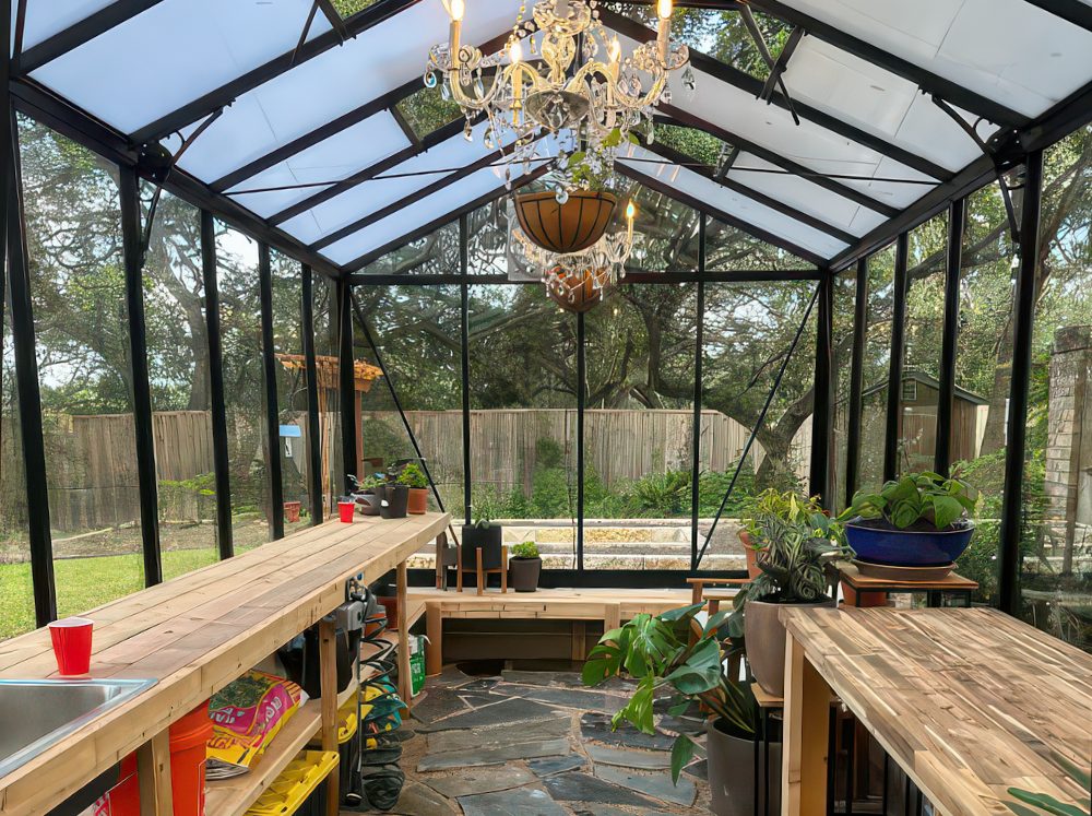 Greenhouse interior showcasing organized storage solutions with wide workbenches and shelving for gardening tools and supplies.