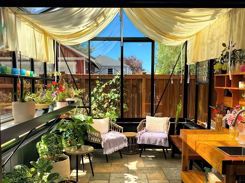 Greenhouse interior with a functional wooden potting bench, integrated sink, comfortable seating, and abundant shelving for plants and tools.