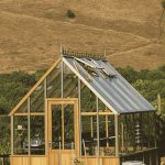 Alton Cheltenham greenhouse front view in the midst of an open field with the greenhouse emporium logo at the top.