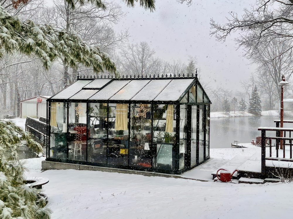 A glass greenhouse on a snowy lake shore. 