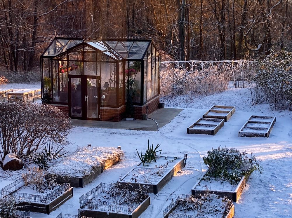 Janssens Orangerie in snow surrounded by garden beds.