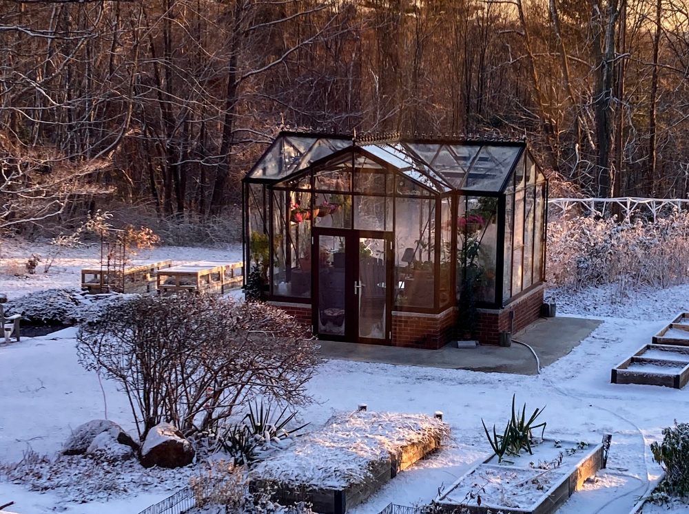 Janssens Orangerie in snow surrounded by garden beds.