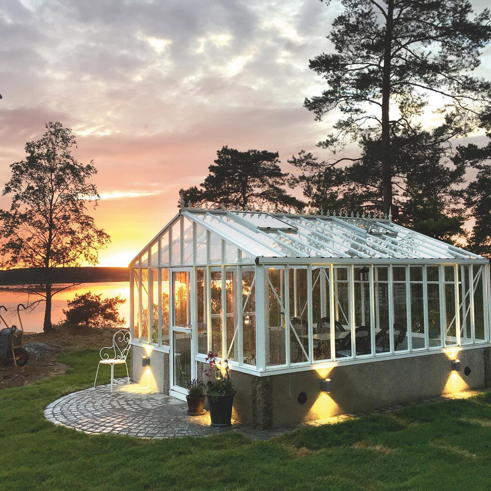 Exterior of glass greenhouse with white frame on waterfront