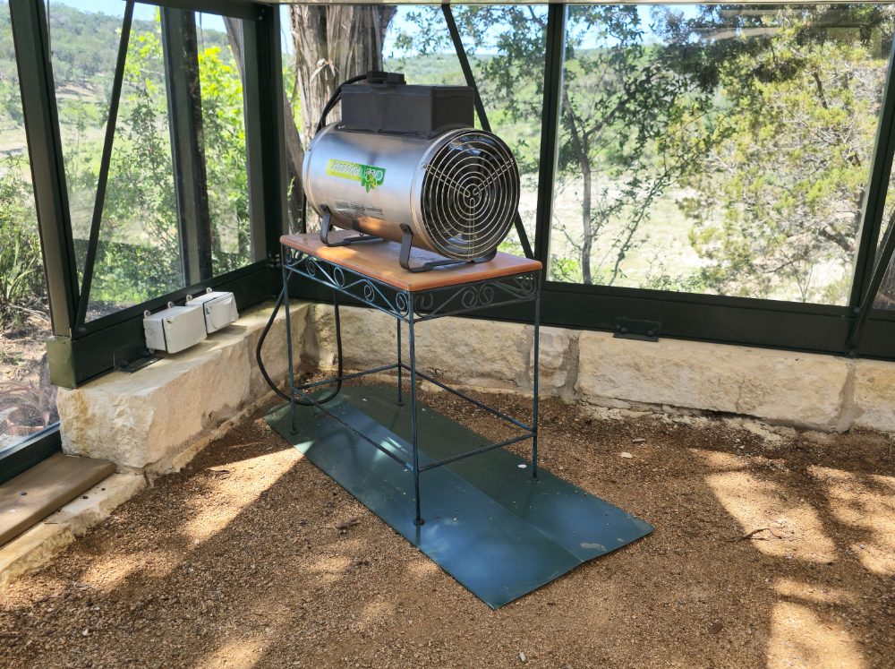 Close up of a heater set up on the inside of a greenhouse set up for winter. 