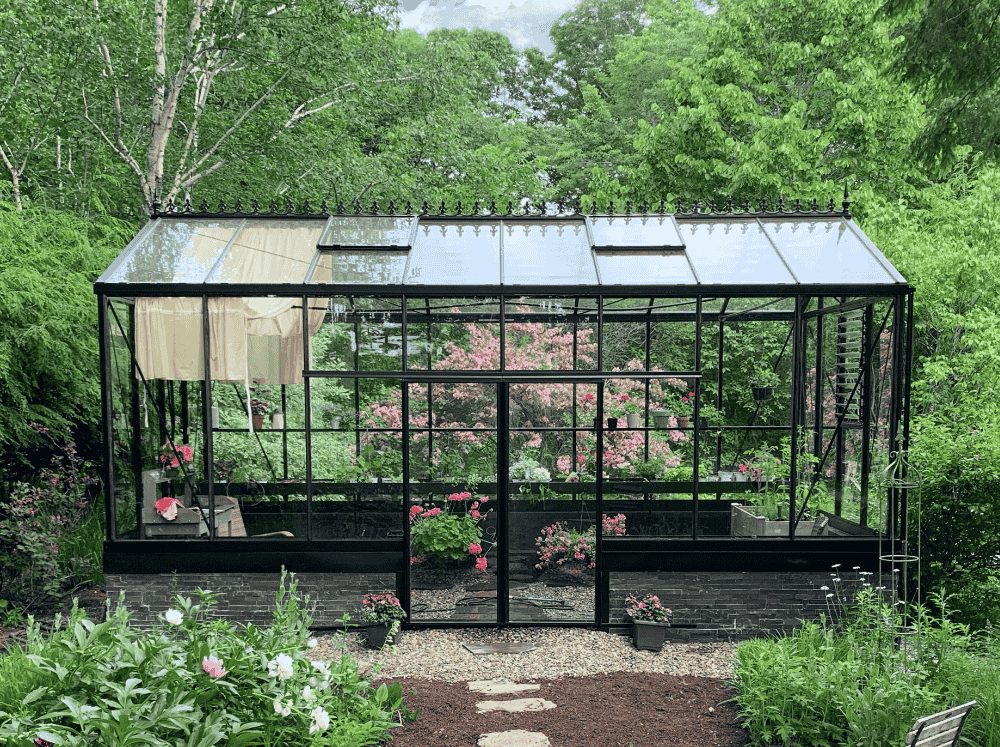 Front view of a glass greenhouse on a brick stem wall