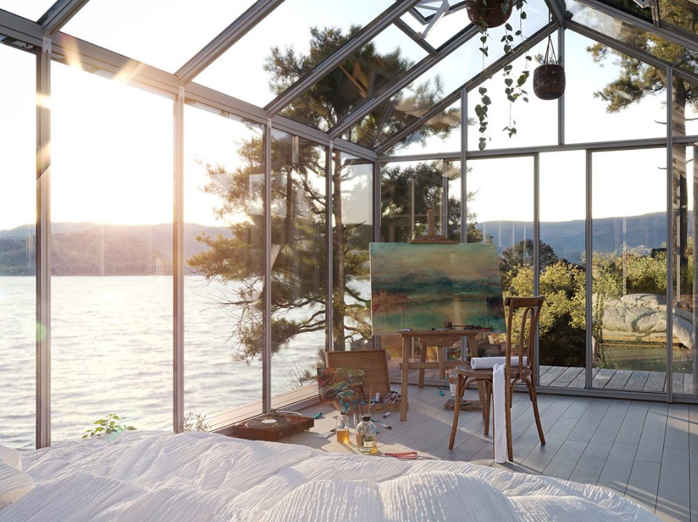 Interior of a greenhouse art studio set up on the waterfront with an easel and a painting in progress.