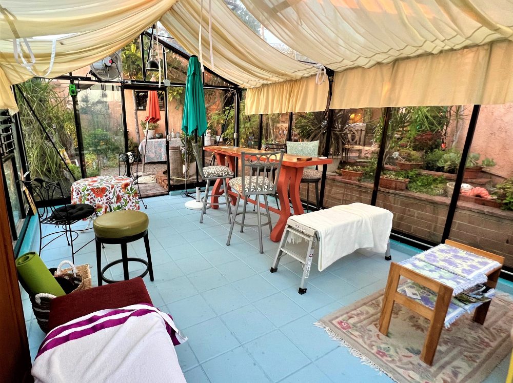 Interior of a greenhouse set up with different colorful tables and chairs. 