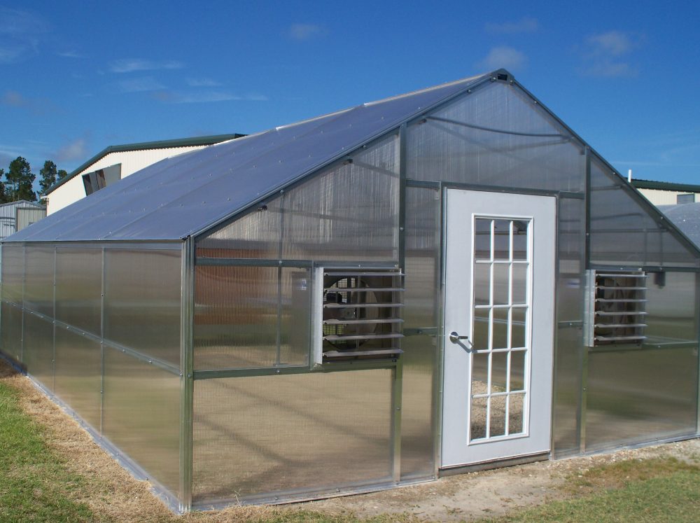 Front corner perspective of extra large polycarbonate Riverstone Industries Educational Greenhouse with two exhaust vents on either side of the front door.