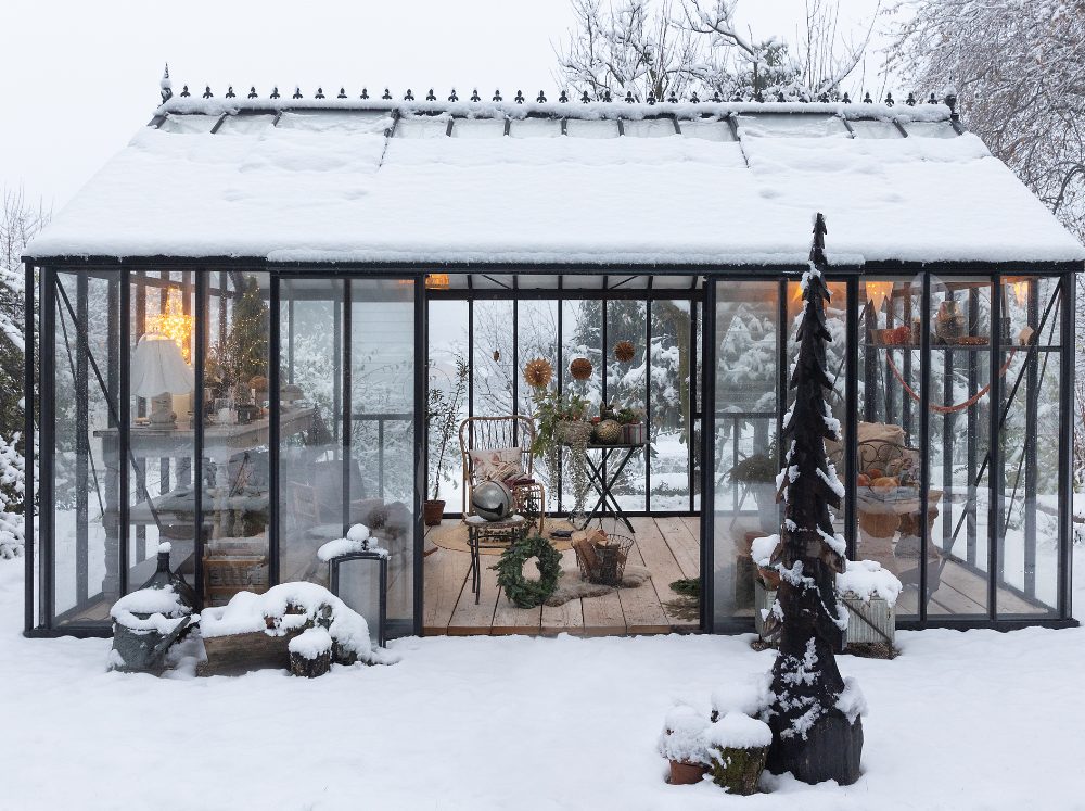 Exterior of a softly lit greenhouse filled with christmas decor as a photo backdrop