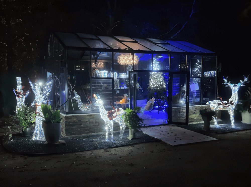 Exterior of a glass greenhouse with christmas light silhouettes surrounding it
